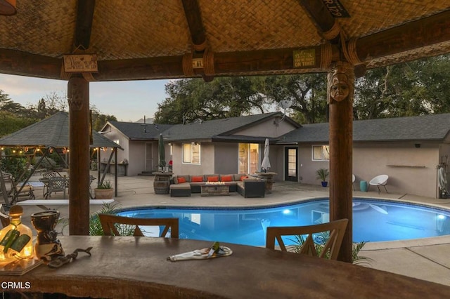 pool at dusk with an outdoor living space, a gazebo, and a patio