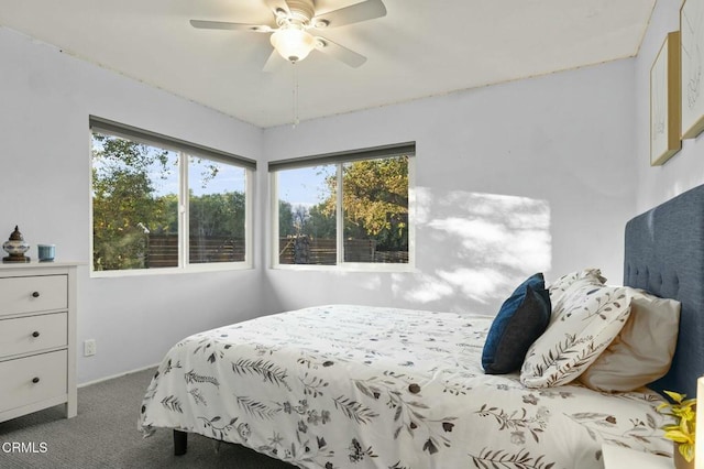 bedroom with ceiling fan, dark carpet, and multiple windows