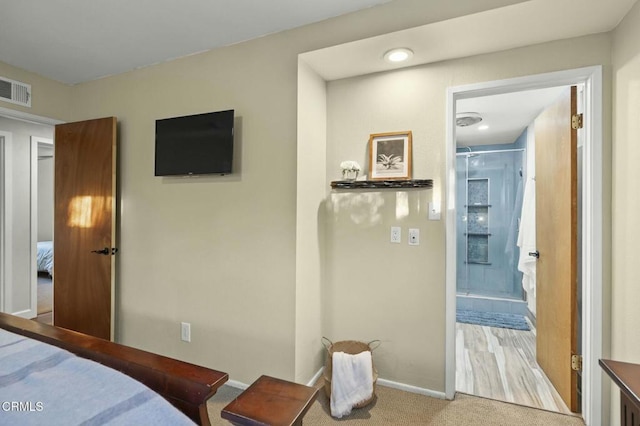 bedroom with ensuite bathroom, carpet floors, visible vents, and baseboards