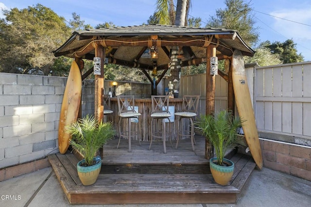 wooden terrace featuring a fenced backyard, outdoor dry bar, and a gazebo