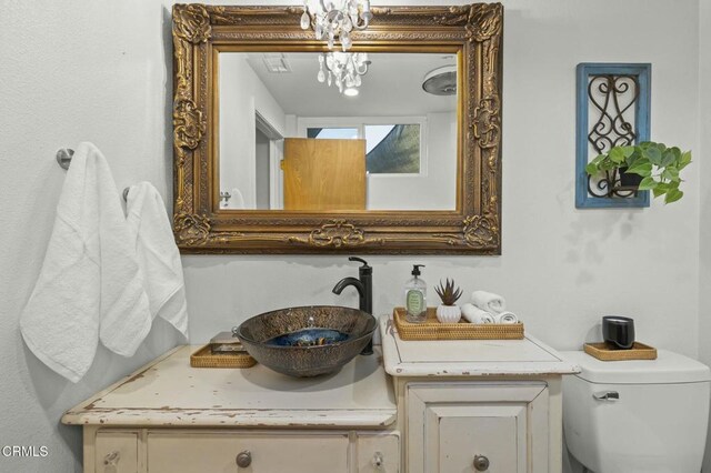 bathroom featuring toilet, an inviting chandelier, and vanity