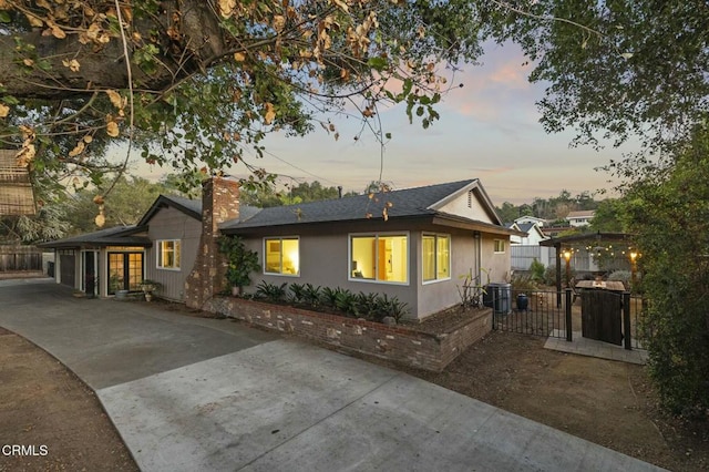 view of front of property with a chimney, central AC, fence, and driveway