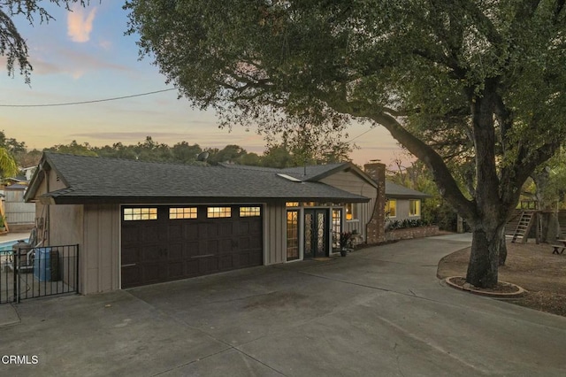 view of front of property with an attached garage, concrete driveway, and roof with shingles