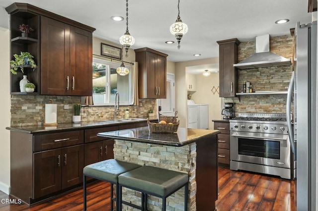 kitchen with appliances with stainless steel finishes, washing machine and clothes dryer, wall chimney range hood, open shelves, and a sink