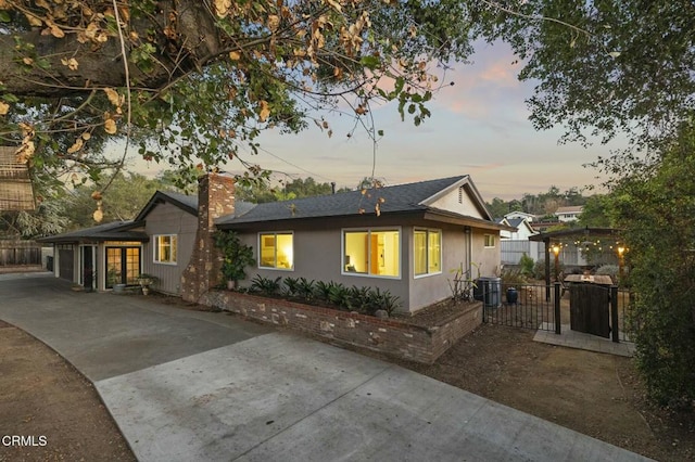 view of front of house with a gate, driveway, central AC, a chimney, and a garage