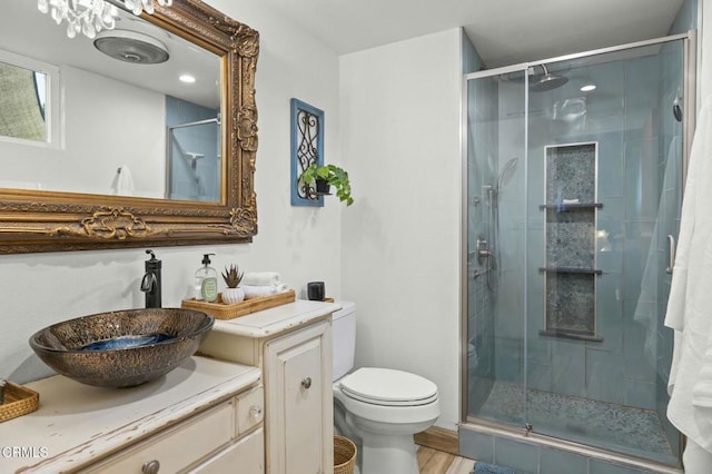 bathroom featuring a shower stall, toilet, vanity, and wood finished floors