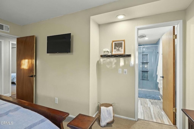 carpeted bedroom with ensuite bath, visible vents, and baseboards