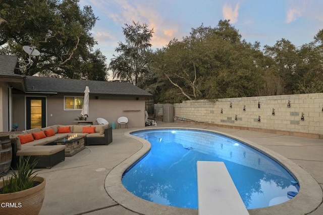 pool at dusk featuring a fenced backyard, a diving board, an outdoor living space with a fire pit, a patio, and a fenced in pool