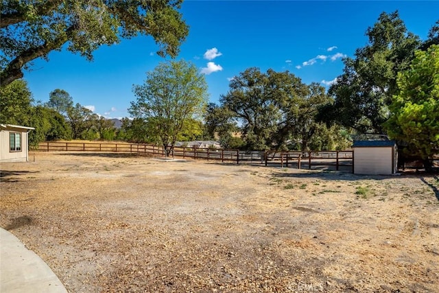 view of yard with a storage shed and a rural view