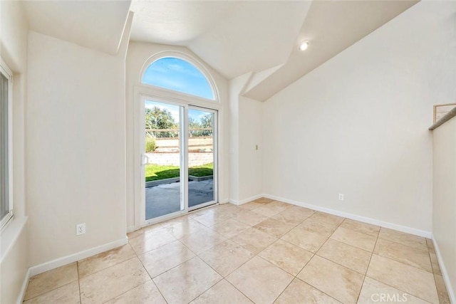 tiled spare room featuring lofted ceiling