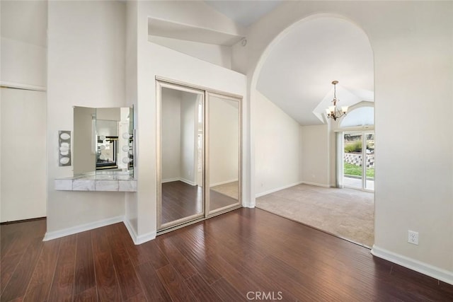 interior space featuring dark hardwood / wood-style floors, a notable chandelier, and vaulted ceiling