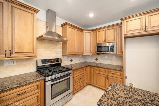 kitchen with backsplash, wall chimney range hood, stainless steel appliances, and dark stone countertops