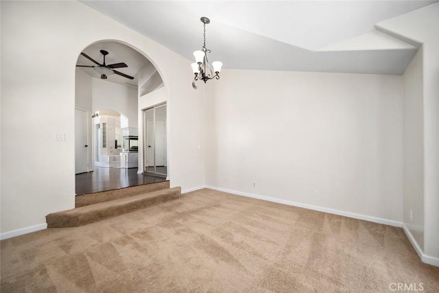 carpeted spare room featuring ceiling fan with notable chandelier and high vaulted ceiling