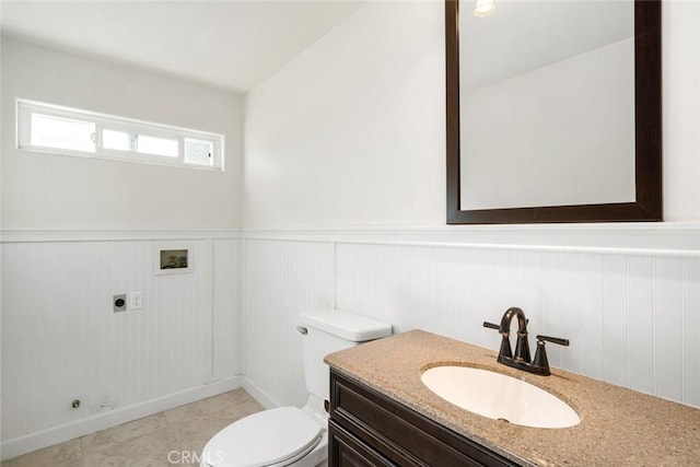 bathroom with toilet, vanity, and wooden walls