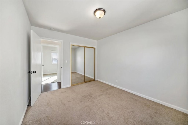 unfurnished bedroom featuring a closet and light colored carpet