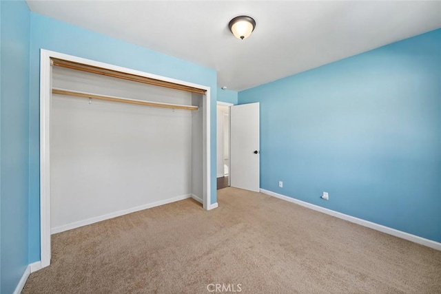 unfurnished bedroom featuring a closet and light colored carpet