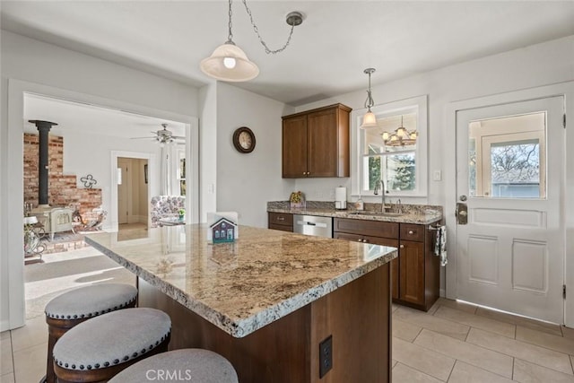 kitchen featuring ceiling fan, a wood stove, pendant lighting, stainless steel dishwasher, and sink