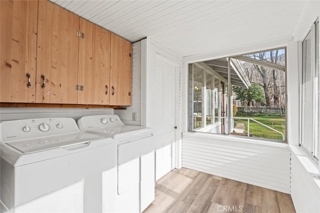 washroom with light wood-type flooring, washing machine and dryer, and cabinets