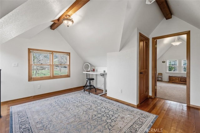 additional living space with a textured ceiling, hardwood / wood-style flooring, and lofted ceiling with beams