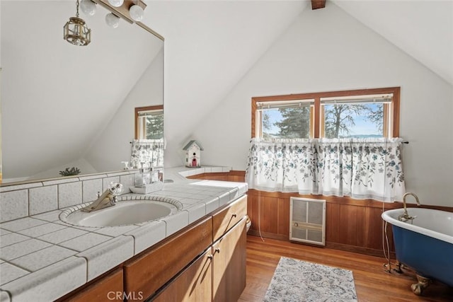 bathroom with vaulted ceiling with beams, hardwood / wood-style flooring, vanity, and a bathing tub