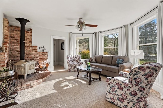 living room featuring ceiling fan, carpet, and a wood stove