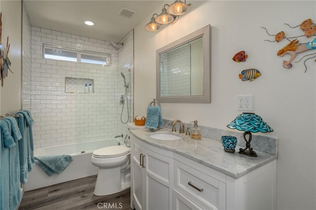 full bathroom with toilet, vanity, wood-type flooring, and tiled shower / bath combo