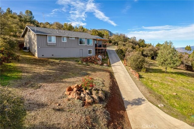 view of front facade with a mountain view, central AC unit, and a front yard