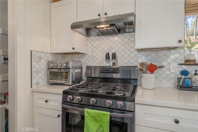 kitchen with decorative backsplash, gas range, range hood, and white cabinetry