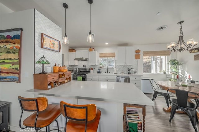 kitchen featuring decorative light fixtures, backsplash, an inviting chandelier, appliances with stainless steel finishes, and white cabinets