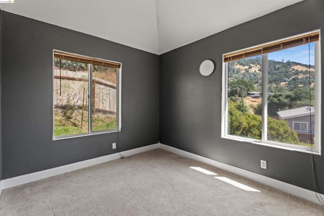 carpeted empty room featuring vaulted ceiling and plenty of natural light