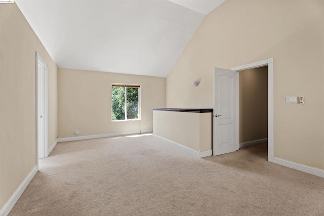 carpeted spare room with vaulted ceiling