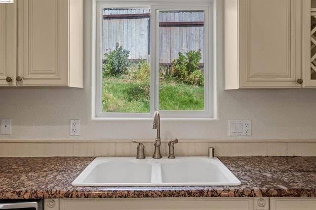 interior details with dishwashing machine, sink, and white cabinetry