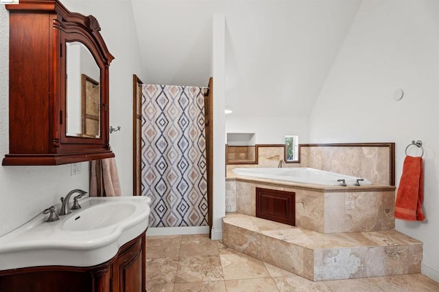 bathroom featuring vanity, vaulted ceiling, and tiled tub