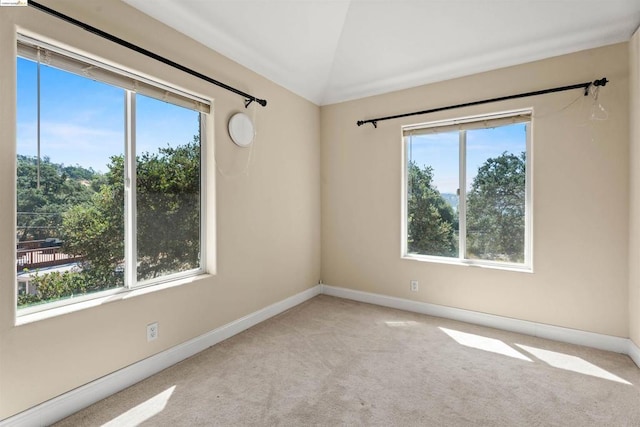 carpeted empty room featuring vaulted ceiling