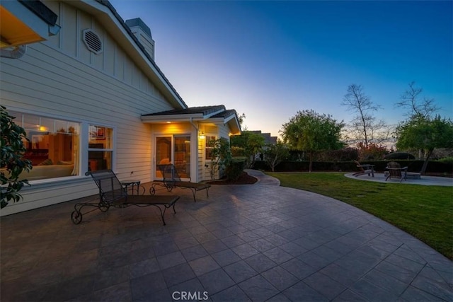 patio terrace at dusk featuring a lawn