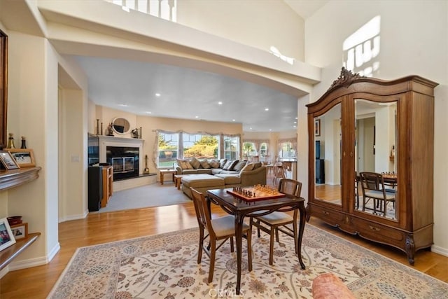 dining space featuring a fireplace, a high ceiling, and light wood-type flooring