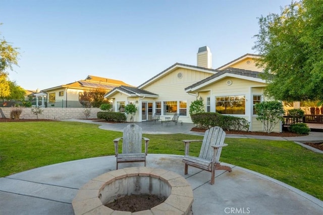 rear view of house featuring a yard, a fire pit, and a patio