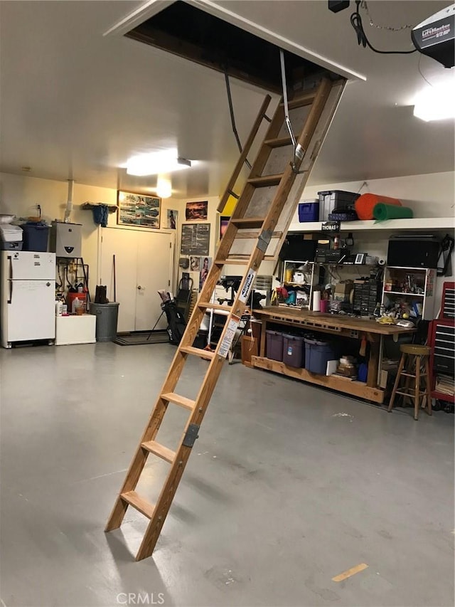 garage featuring a garage door opener, a workshop area, and white fridge