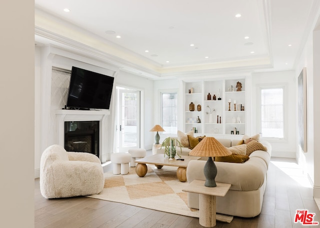 living room with a raised ceiling, light wood-type flooring, and a fireplace