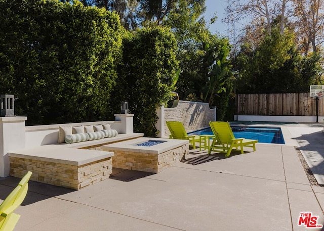 view of patio with a fenced in pool and a fire pit