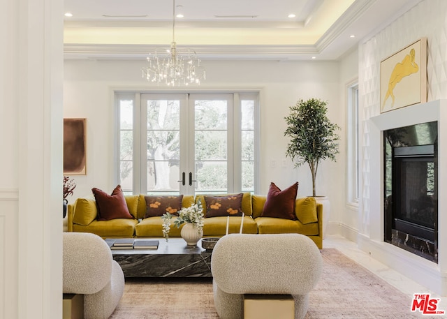 living room featuring a chandelier, a tray ceiling, a high end fireplace, and french doors