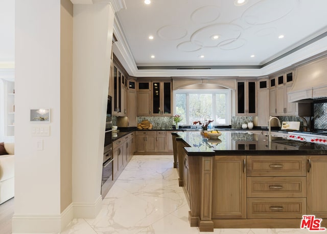 kitchen featuring a center island with sink, stainless steel oven, backsplash, crown molding, and sink