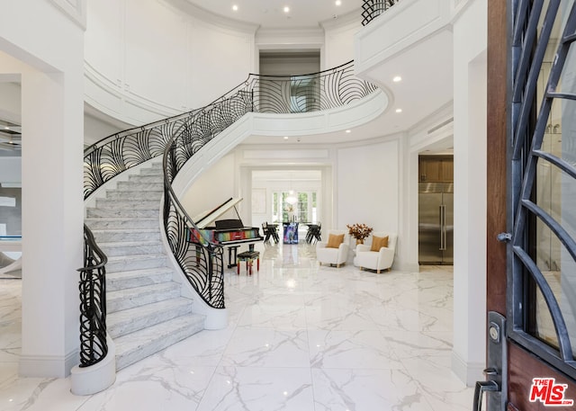 foyer entrance with a towering ceiling and ornamental molding