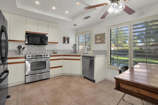 kitchen with a tray ceiling, sink, white cabinets, and black appliances