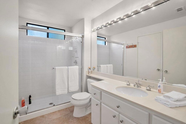 bathroom featuring tile patterned floors, vanity, toilet, and a shower with door