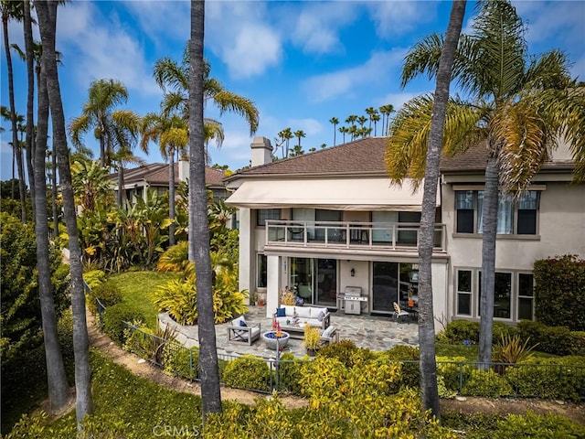 rear view of house featuring a balcony, outdoor lounge area, and a patio