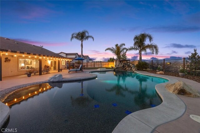 pool at dusk with a patio area