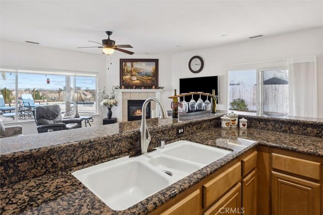 kitchen featuring ceiling fan, a fireplace, sink, and plenty of natural light