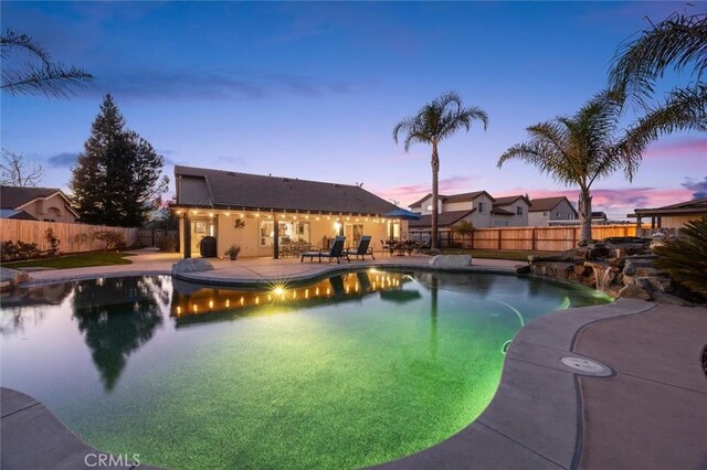 pool at dusk featuring a patio area