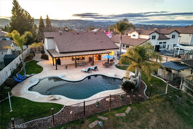 pool at dusk featuring a lawn and a patio